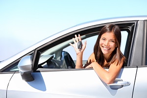 woman leaning out the car window holding keys smiling at camera
